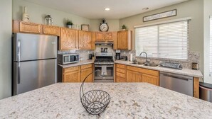 A modern kitchen with wooden cabinets, stainless steel appliances, granite countertops, and a central island. - 777Rentals - 4BRs/3BA - Wet and Wild Convenience (Las Vegas)