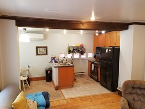 Enjoy cooking in this well-equipped kitchen with a central island, sink, and stove, complemented by a dining area with a chair and sofa.