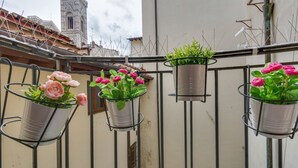 Três vasos com plantas e flores numa varanda.