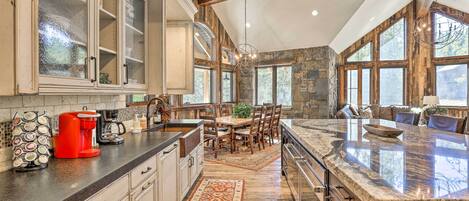 A kitchen with a large island, wooden cabinets, and a stone accent wall.