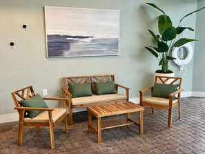 A seating area with a wooden sofa and two chairs, a small wooden table, and a large potted plant. - Universal Studios, International Dr (Orlando)