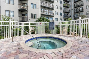A swimming pool with a white fence and chairs, surrounded by a multi-story building with balconies. - Universal Studios, International Dr (Orlando)