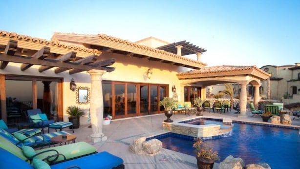 Un área de piscina con sillones reclinables y una pérgola.