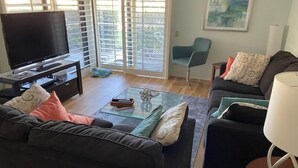 Ein Wohnzimmer mit einer Couch, einem Couchtisch, einem Fernseher und einem Sessel.
