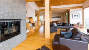 A modern living room with a fireplace, wooden flooring, and a sectional sofa. - Exclusive 5 Bedroom Luxury Chalet, Niseko Chalet 1004 (Niseko)