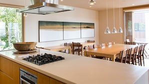 A modern kitchen with a large island, stainless steel range hood, pendant lights, and a large window overlooking greenery. - Exclusive 5 Bedroom Luxury Chalet, Niseko Chalet 1004 (Niseko)