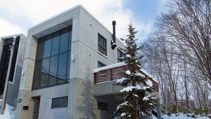 Un edificio moderno con amplios ventanales, fachada de hormigón y paisaje cubierto de nieve.