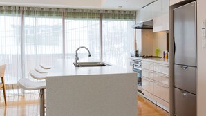 Una cocina moderna con una isla central, electrodomésticos de acero inoxidable y vistas amplias a través de grandes ventanales.