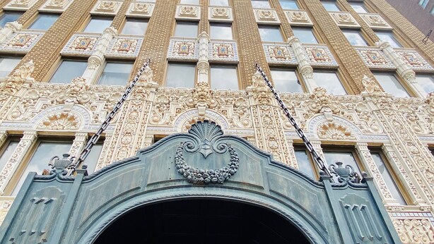 Un immeuble imposant, doté de détails architecturaux raffinés, notamment des colonnes décoratives et une grande entrée en arc de cercle.
