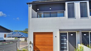 Ein modernes, zweistöckiges Haus mit Garage, Solaranlage und gepflegtem Rasen.