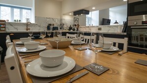 A modern kitchen with marble countertops, a dining area set for six with white plates and glasses, and a built-in oven. - Two separate 2-bedroom apartments, joined by a private hallway. Kendal Town Centre (Kendal)