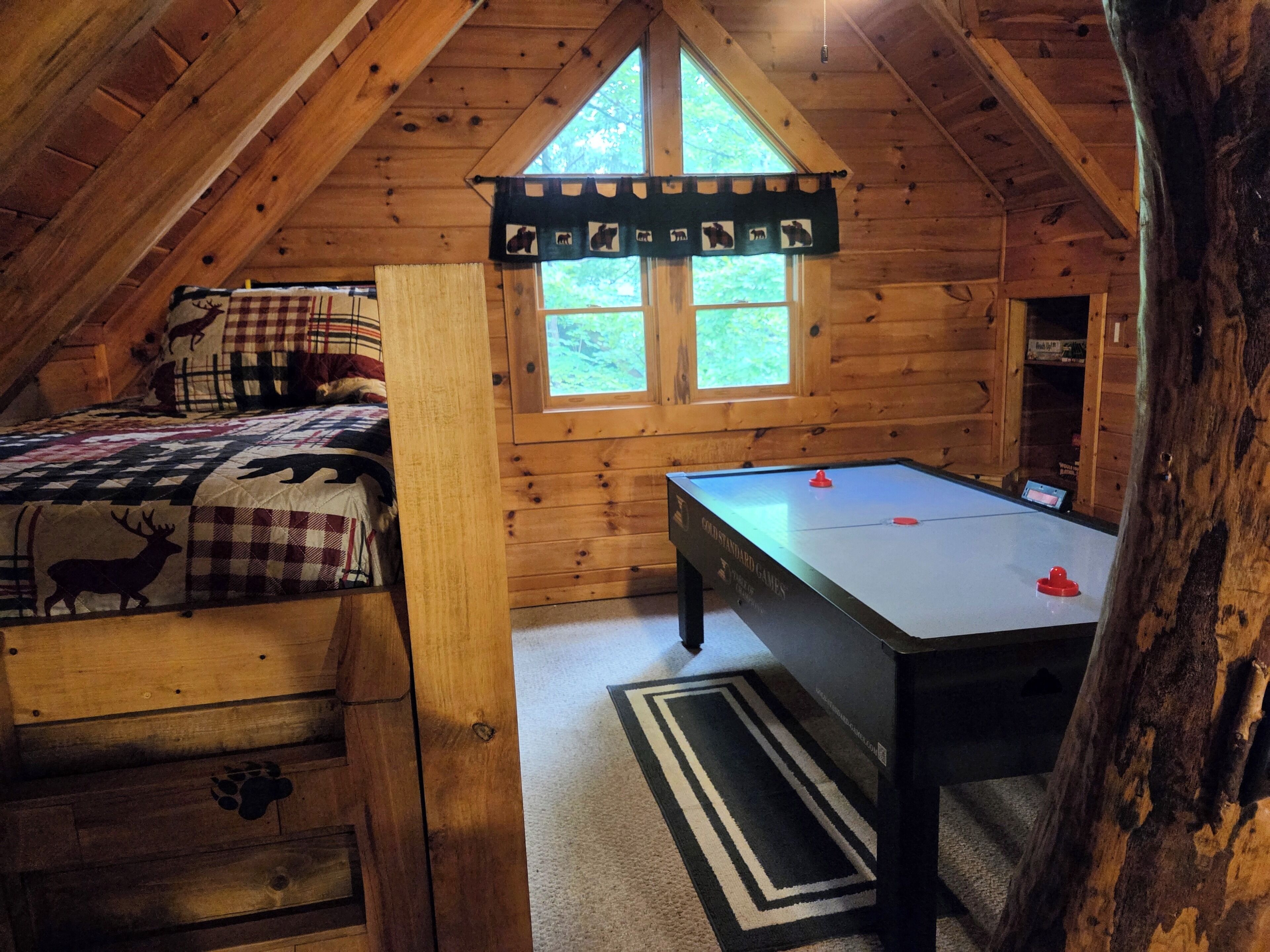 Una camera accogliente con letto a soppalco, tavolo da biliardo e finestra con vista sul verde.