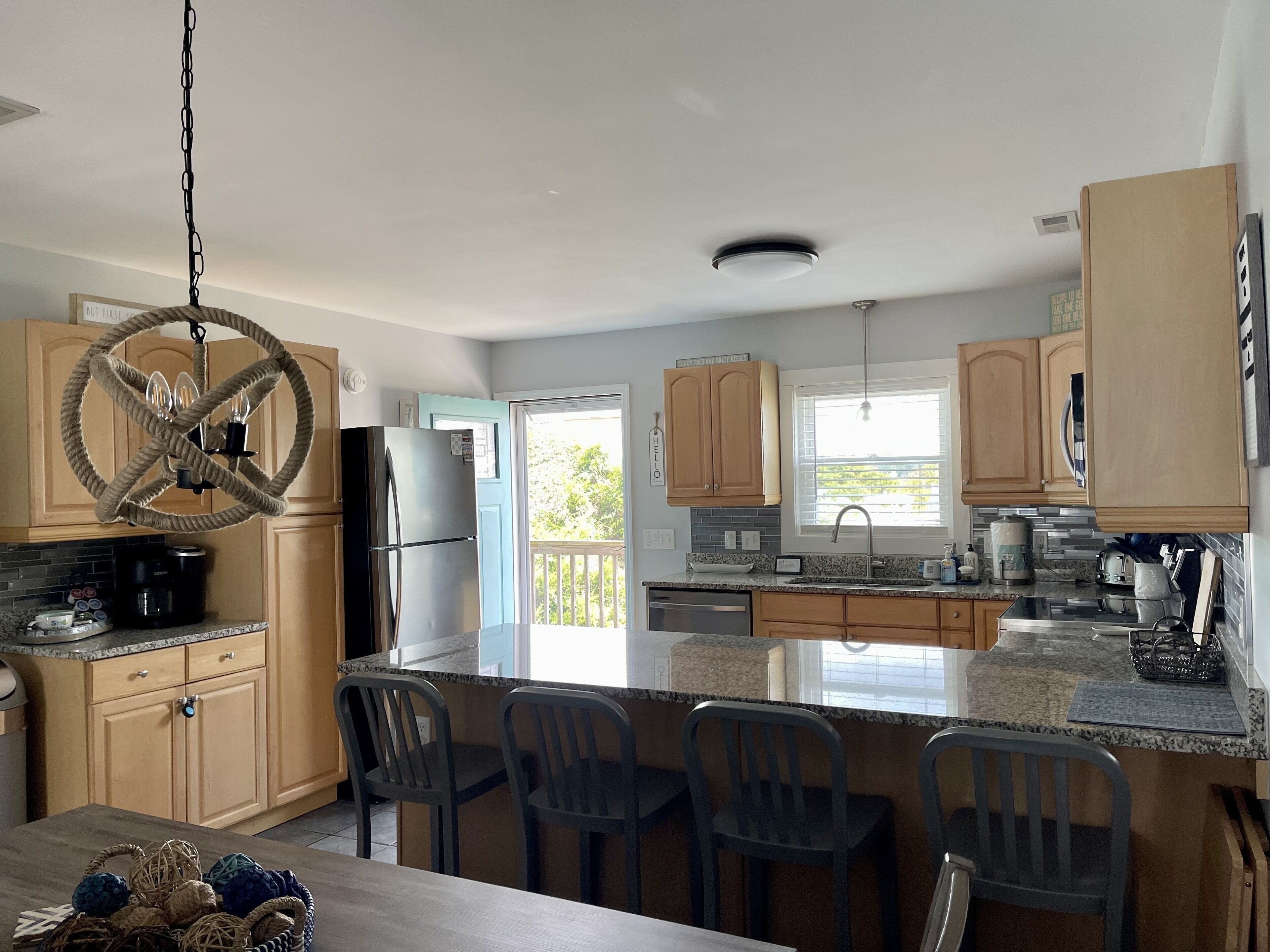 A modern kitchen with wooden cabinets, a stainless steel refrigerator, and a large island with bar stools.