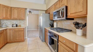 Una cocina con armarios de madera, microondas, refrigerador, estufa y tostadora.