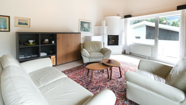 Un salon moderne avec un plafond en bois, des canapés blancs, un tapis à motifs et une cheminée.