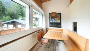Un intérieur moderne avec un plafond en bois, de grandes fenêtres, une table en bois et un banc.