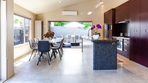 Een moderne keuken met donkerhouten kastjes, een granieten eiland en een eethoek met een tafel en stoelen.