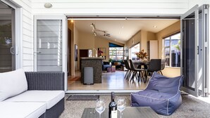 Een open schuifdeur leidt naar een eetgedeelte met een tafel voor twee personen, een bank en een stoel.