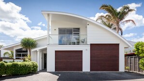 Een modern huis met twee verdiepingen, een gebogen dak, een groot raam en een garage.