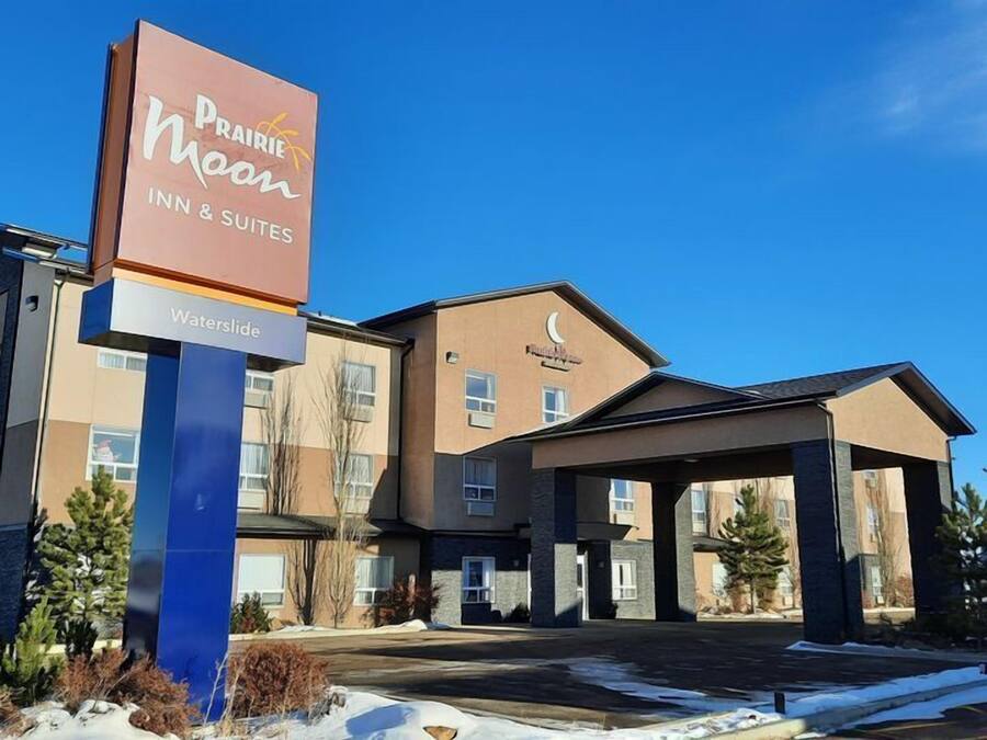 Prairie Moon Inn & Suites gebouw met een opvallend bord, een overdekte ingang en een parkeerplaats met sneeuw.
