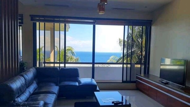 Ein modernes Wohnzimmer mit einem großen Schiebeglastür, die auf einen Balkon mit Meerblick führt.