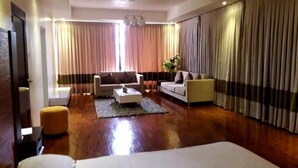 Ein modernes Hotelzimmer mit einem großen Bett, zwei Sofas, einem Couchtisch und einem kleinen Beistelltisch.