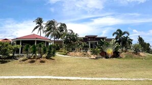 Ein Resort mit einem überdachten Pavillon, Palmen und blauem Himmel.