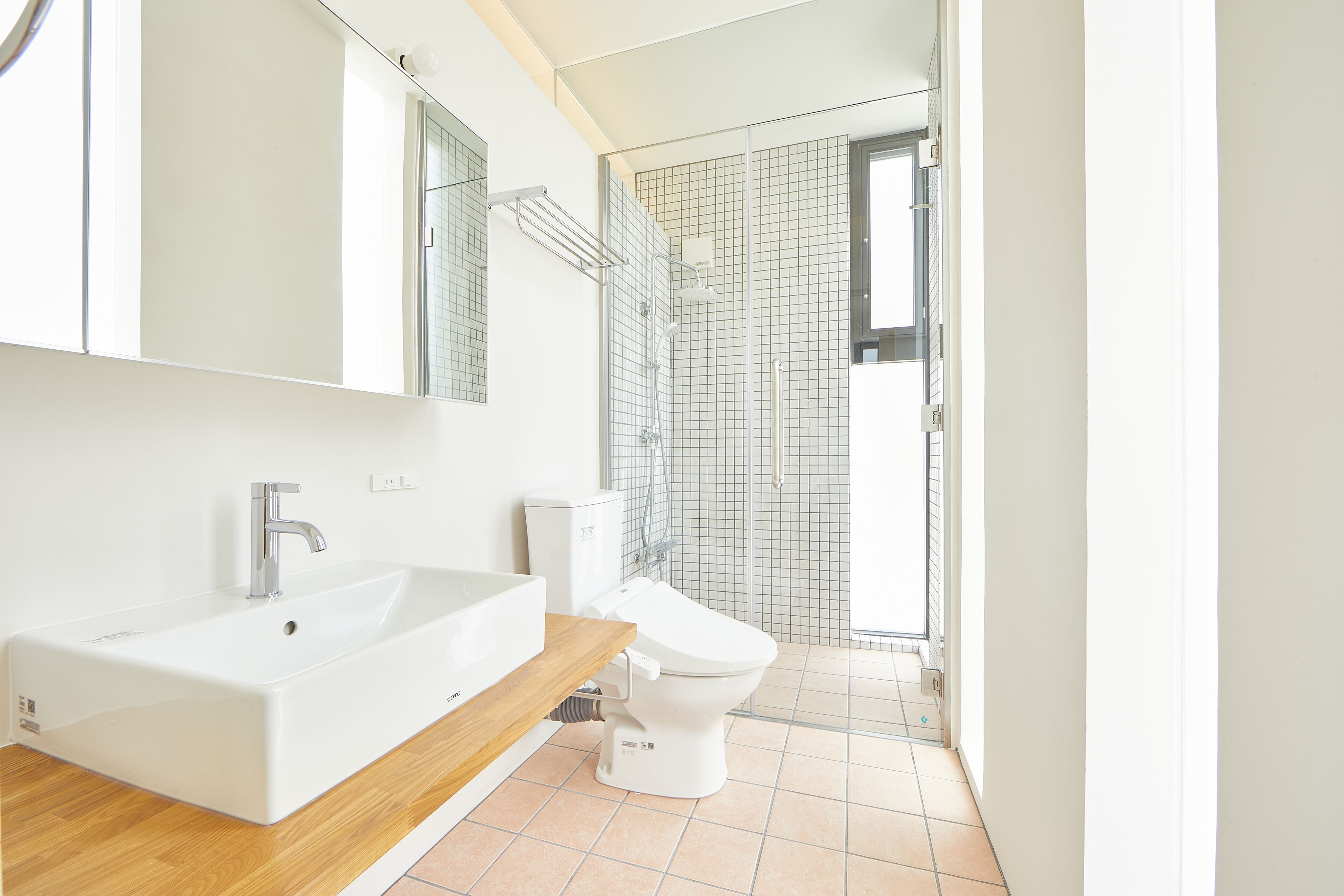 Ein modernes Badezimmer mit einem großen weißen Waschbecken, einer Toilette und einer Duschkabine.