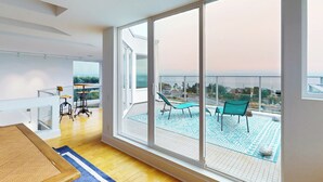 Un salon moderne doté d’une grande porte-fenêtre coulissante donnant sur un balcon aménagé avec des sièges d’extérieur.