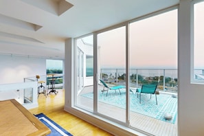 A modern living room with a large sliding glass door leading to a balcony with outdoor seating.