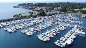 Un port de plaisance où sont amarrés de nombreux bateaux, avec une vue sur le front de mer et des bâtiments en arrière-plan.