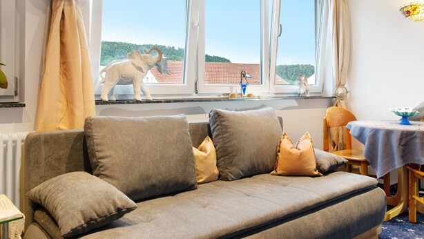 Una habitación con sofá, una mesa y vistas a un edificio de tejado rojo.
