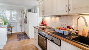 Una cocina con armarios blancos, encimera de madera, pileta de acero inoxidable y horno empotrado.