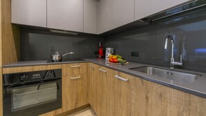 Una cocina moderna con armarios de madera, electrodomésticos de acero inoxidable y un lavamanos grande.