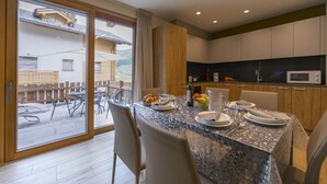 Un comedor con una mesa dispuesta para cuatro, una cocina con electrodomésticos modernos y vistas al patio exterior.