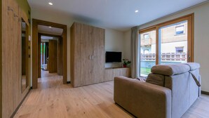 Una sala de estar moderna con un sofá, un televisor de pantalla plana y un mueble de madera.