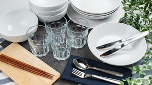 A neatly arranged table setting with white plates, bowls, glasses, and cutlery. - Gracia Hotel (Osaka)