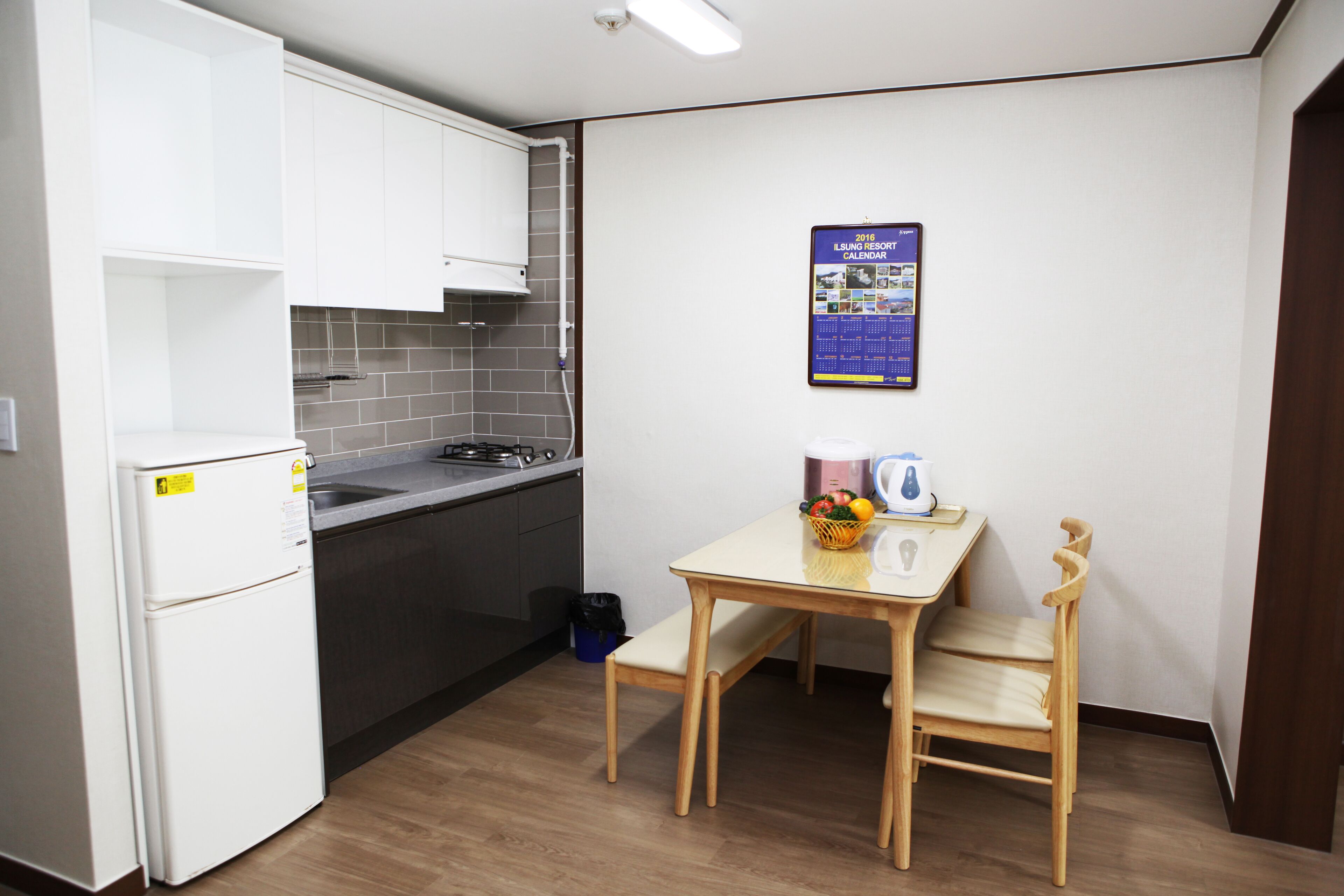 A compact kitchen with white cabinets, a stove, and a small table with chairs.