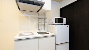 Eine kompakte Küchenzeile mit integriertem Mikrowellenherd, Spüle und kleinem Kühlschrank.