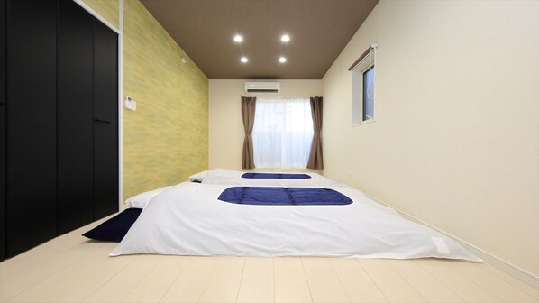 Une chambre d’hôtel avec un grand lit, une porte, un appareil de climatisation et une fenêtre avec des rideaux.