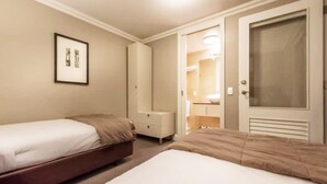 Una habitación de hotel con dos camas, un armario, una mesita de noche y un cuadro en la pared.