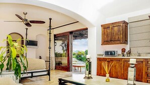 A bedroom with a bed, a ceiling fan, a TV, and a view of the garden. - Exclusive Beachfront Villa with Private Pool Awaits You (Cabo San Lucas)