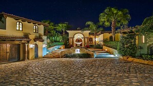 A courtyard with a fountain, palm trees, and a building with a tiled roof. - Exclusive Beachfront Villa with Private Pool Awaits You (Cabo San Lucas)