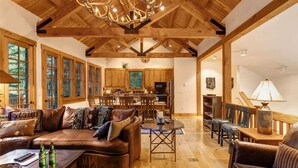 A spacious living room with a large brown leather sofa, wooden dining table, and a chandelier. - Abode at the Homestead, walk to slopes, hot tub (Teton Village)