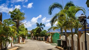 A residential street with houses, palm trees, and a clear blue sky. - Villa Tanya at Platinum (Rawai)