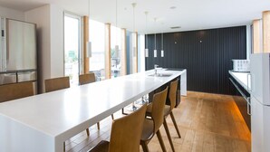 Une cuisine moderne dotée d’un grand îlot central, de chaises en bois, d’un four encastré et d’une grande fenêtre.