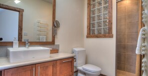 Une salle de bain avec un grand miroir, un lavabo, des toilettes et un espace douche.