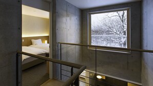 A modern hotel room with a large window, a bed, and a staircase.