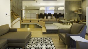 A modern living room with a staircase, a dining area, and a fireplace.