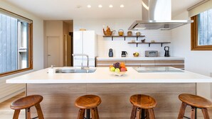 A modern kitchen with a large island, bar stools, and a fruit bowl. - Luxury 5 Star 3 Bedroom Chalet, Niseko Chalet 1005 (Niseko)